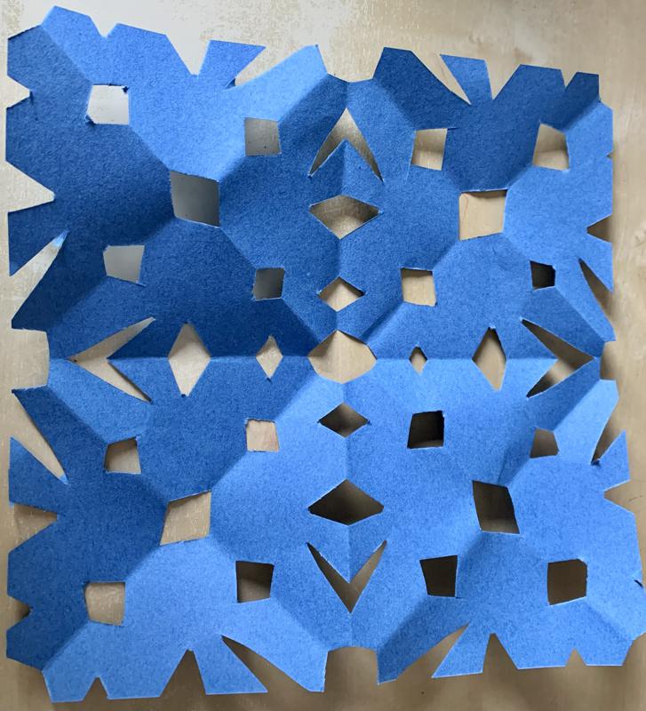A square piece of blue paper with various holes cut into it.