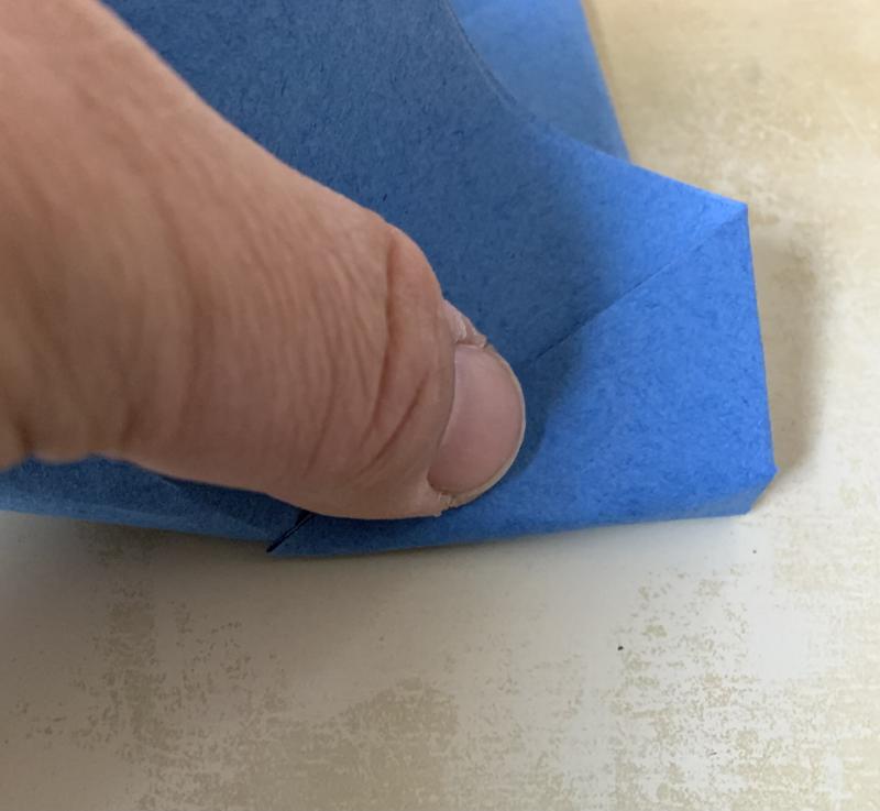A thumb presses into the paper to make the described fold.